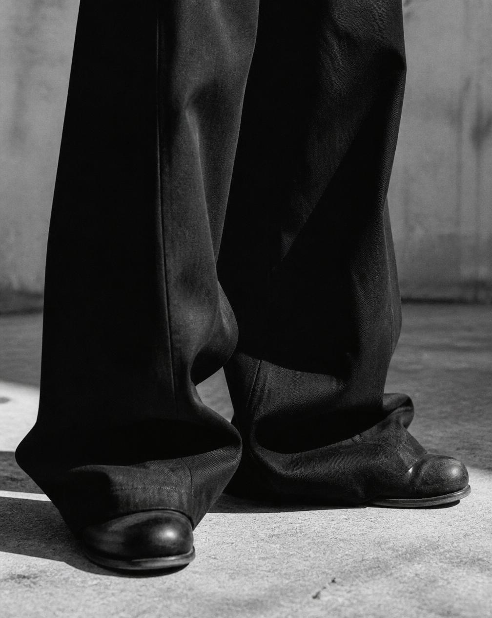 Baggy trousers draping over boots on concrete