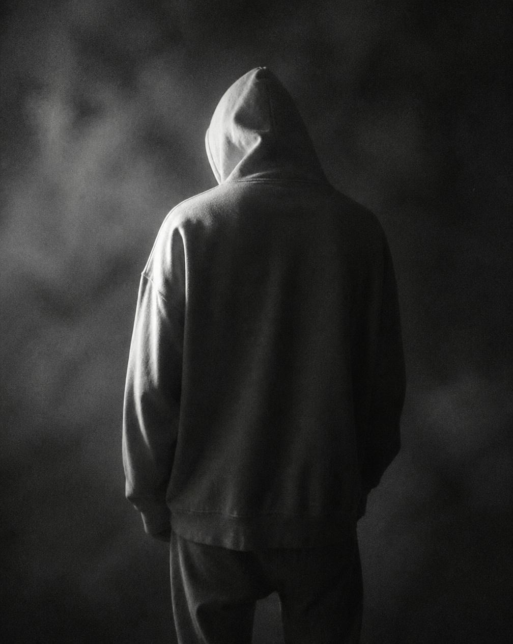 Figure from behind in an oversized bone hoodie in fog